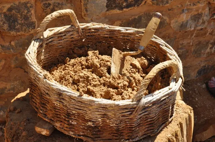 کارگر در حال اعمال ملات بین آجرها در یک دیوار بنایی