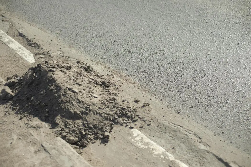 تجمع خاک و گل و لای در کناره‌های جاده که نشان‌دهنده نیاز به تمیزکاری آبروهای جاده‌ای است